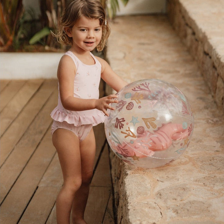 Kind spielt mit dem transparenten 3D Strandball Ocean Dreams Pink mit Seepferdchen-Motiv auf der Terrasse im Garten. Der aufblasbare Strandball mit 35 cm Durchmesser eignet sich ideal für Garten, Pool, Strand und sommerlichen Spielspaß.