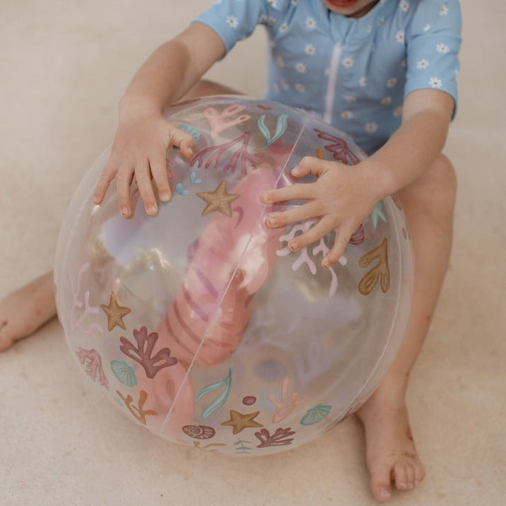 Kind spielt mit dem transparenten 3D Strandball Ocean Dreams Pink mit Seepferdchen-Motiv. Der aufblasbare Strandball mit 35 cm Durchmesser eignet sich ideal für Garten, Strand, Pool und sommerlichen Spielspaß.