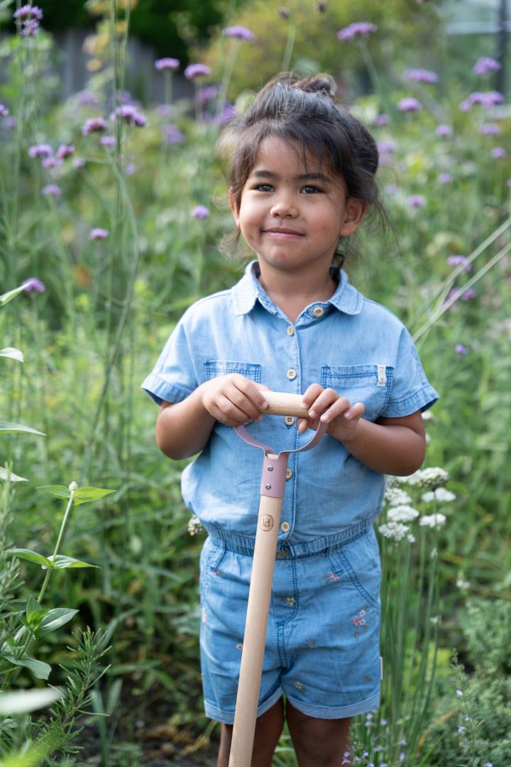 Kind mit personalisierter Kinderschaufel in Rosa und eingraviertem Namen im blühenden Garten – hochwertiges Gartenwerkzeug für Kinder ab 3 Jahren, ideal als personalisiertes Geschenk zum Geburtstag, Kindergartenstart oder für kleine Gartenfreunde von Schmatzepuffer.