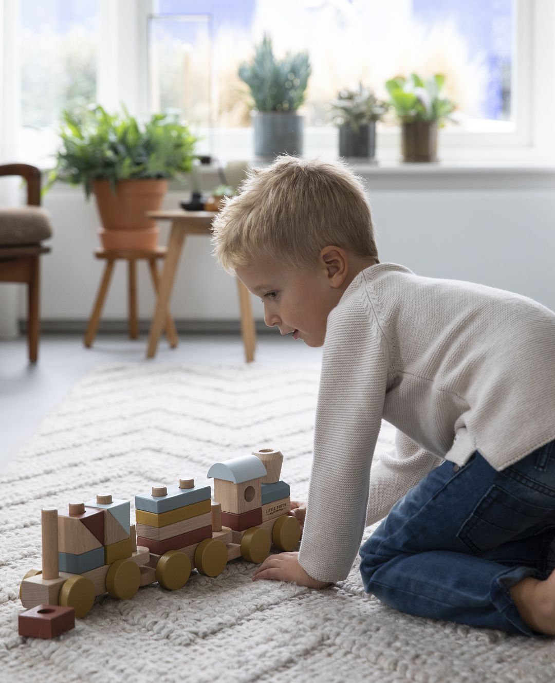 Kind spielt im Kinderzimmer mit dem Holzzug Pure & Nature und den farbigen Steckbausteinen aus Holz