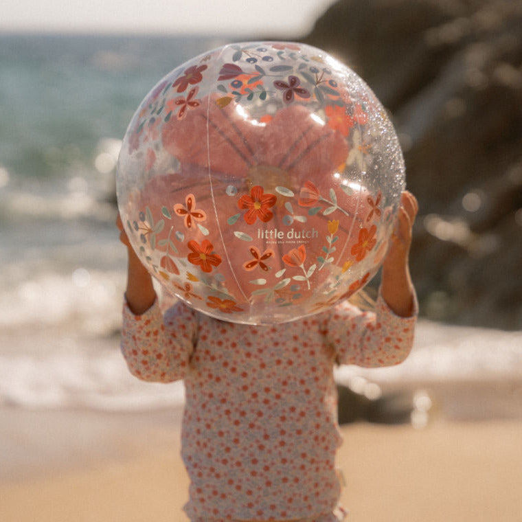 Kind hält Strandball am Strand im Sonnenlicht – sommerlicher Spielspaß im Urlaub für Kinder