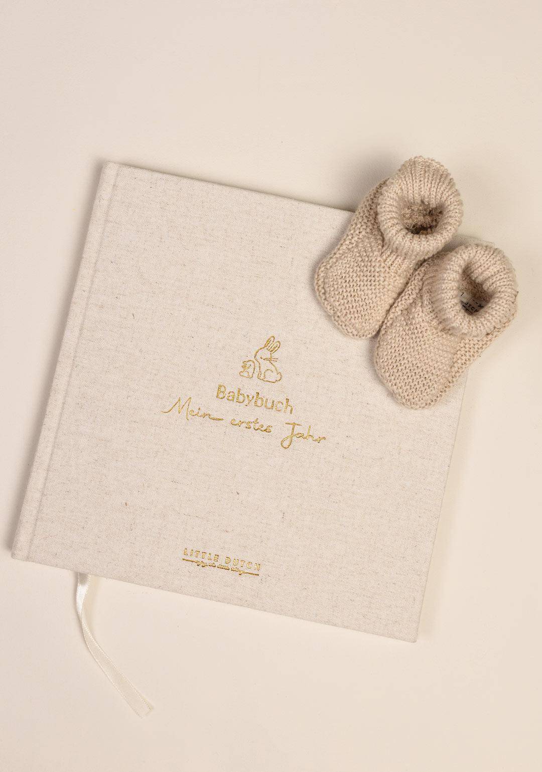Baby Tagebuch Mein erstes Lebensjahr mit hochwertigem Leineneinband neben Babyschühchen – liebevolles Erinnerungsalbum für Fotos, Meilensteine und besondere Momente im ersten Babyjahr, ideales Geschenk zur Geburt.