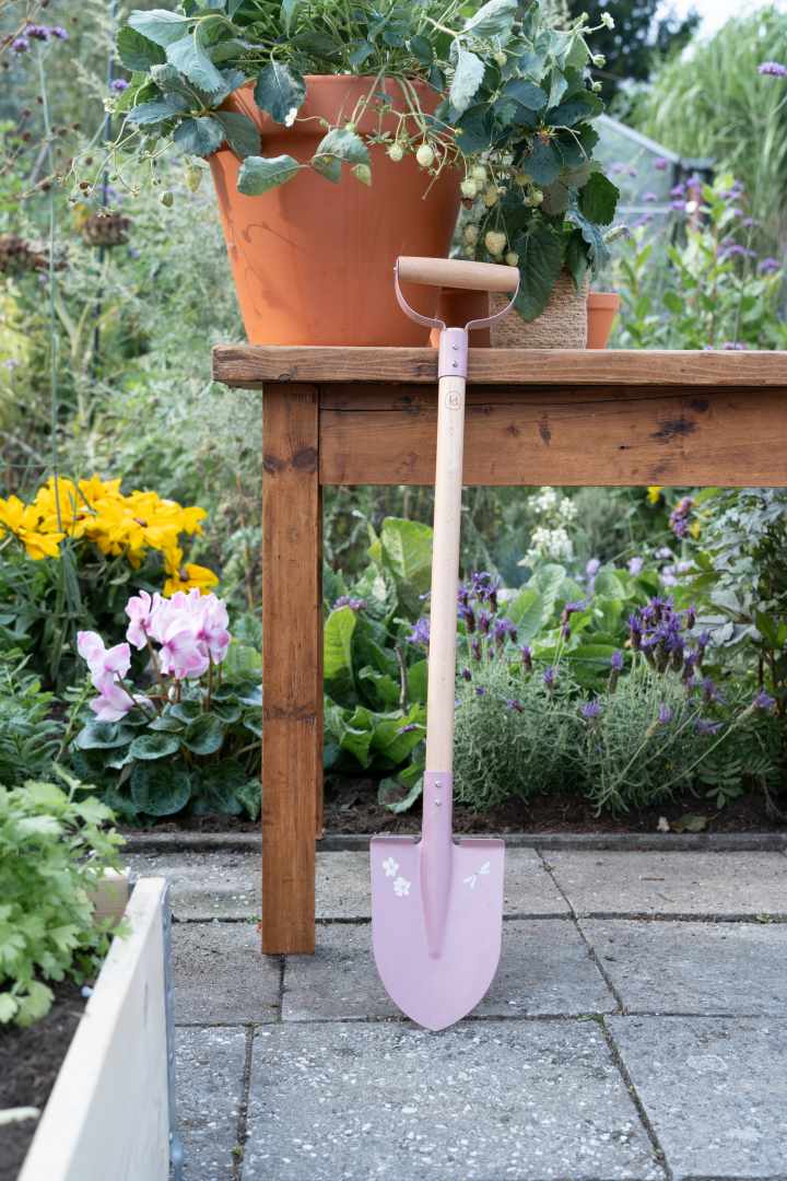 Personalisierte Kinderschaufel in Rosa mit Namen im blühenden Garten – hochwertiges Gartenwerkzeug für Kinder ab 3 Jahren, ideal für Gartenarbeit, Sandkasten und Strand. Individuell personalisiert bei Schmatzepuffer als besonderes Geschenk zum Geburtstag oder Kindergartenstart.