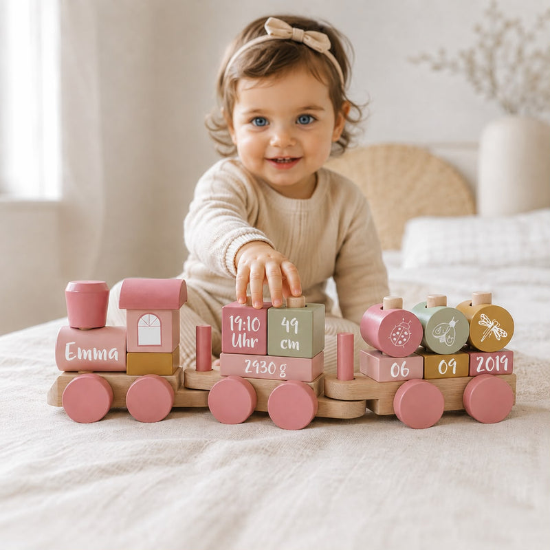 Baby mit personalisiertem Holzzug in Rosa und Pink mit Name und Geburtsdaten als Geschenk zur Geburt