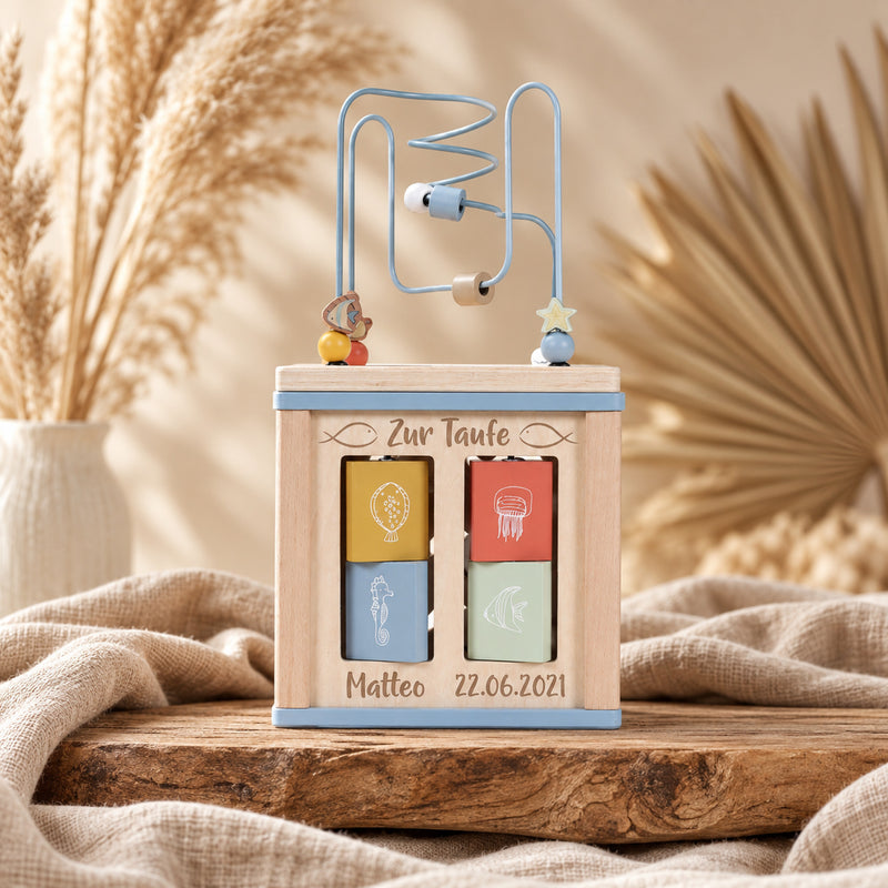 Personalisierter Motorikwürfel Ocean aus Holz zur Taufe mit Name und Taufdatum in warmer Boho-Kulisse